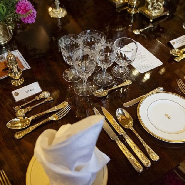 Close-up of a formal dining table set with elegant crystal glassware, polished silver cutlery, and white napkins, showcasing refined table etiquette.